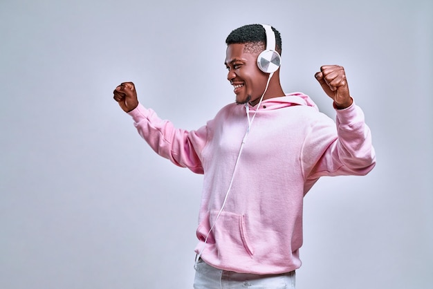 Young attractive black student man with headphones and mobile phone listening to music dancing