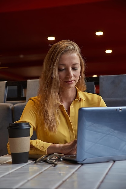 Young attractive blond cauasian woman sitting at coffe shop working on laptop