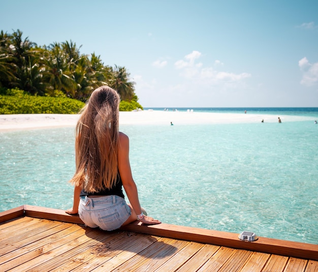 Young attractive blonde girl with perfect sport body in bikini on the tropical summer beach