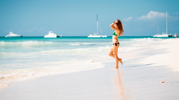 Young attractive blonde girl with perfect sport body in bikini on the tropical summer beach