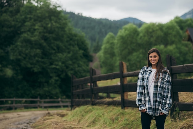 A young attractive Caucasian female sitting on a fence and posing at camera