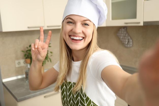 Young attractive chef woman doing selfie in kitchen room