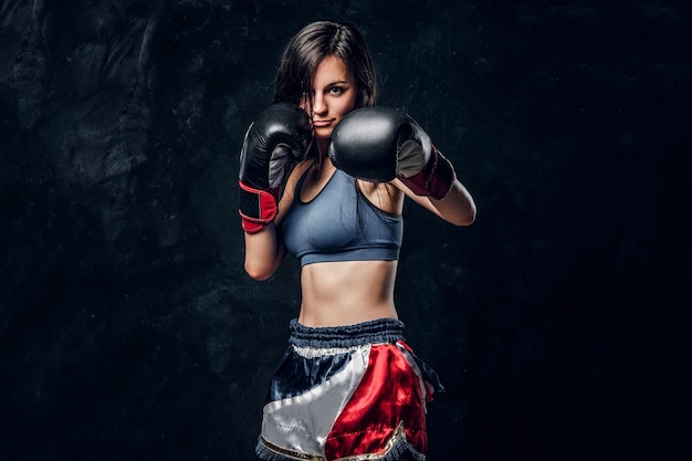 Young attractive female boxer with long hair and boxing gloves is ready to fight.