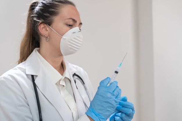 Young attractive female doctor preparing vaccine syringe wearing preventive mask and blue gloves cor