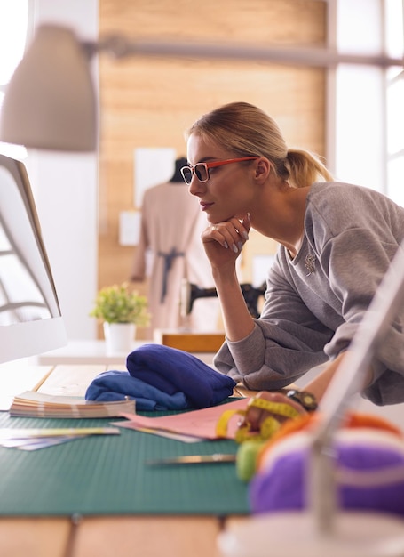 Young attractive females fashion designers leaning on office desk working with a laptop