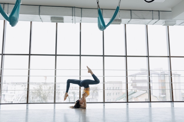 Young attractive girl doing fitness exercises with yoga on the floor. panoramic windows