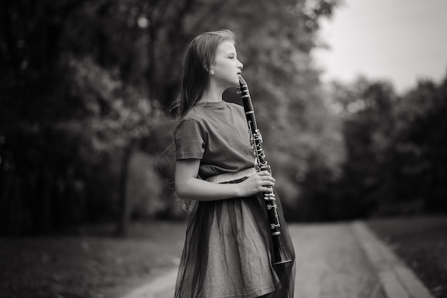 Photo young attractive girl playing clarinet, ebony in fall park