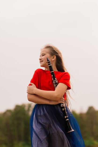 Photo young attractive girl playing clarinet, ebony in fall park