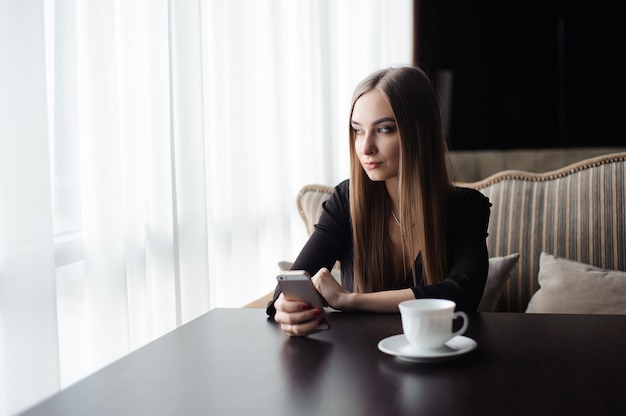 Young attractive girl sitting alone near big window