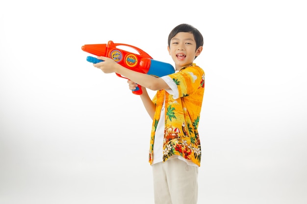 Young attractive happy Asian boy hold water gun in Hawaiian shirts on white background with clipping path Songkran Thailand