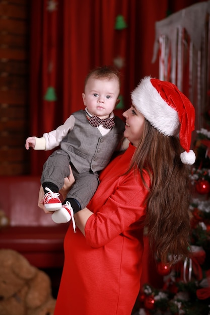 Young attractive happy mother in santa's hat have a good time with her son at home near christmas tree. Family, happiness, holidays, new year concept