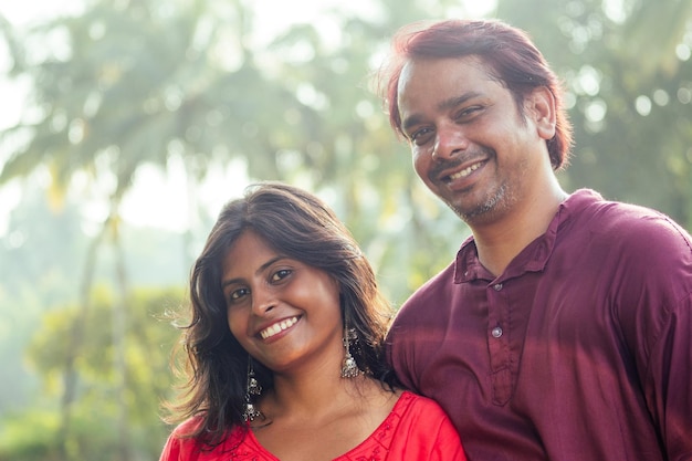 Young attractive indian couple feeling tenderness and hugging each other at sunset light palms tree background