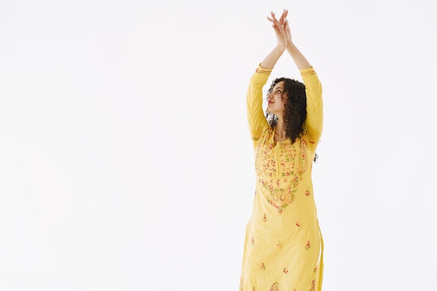 Young attractive Indian woman in traditional dress. Woman dancing against white background.