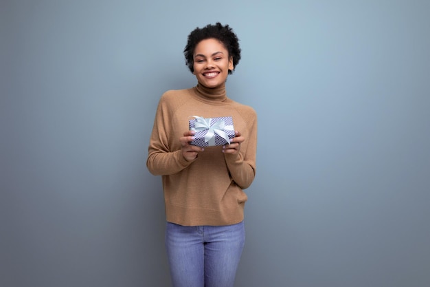 Young attractive latin woman with black afro ponytail giving gift box for anniversary