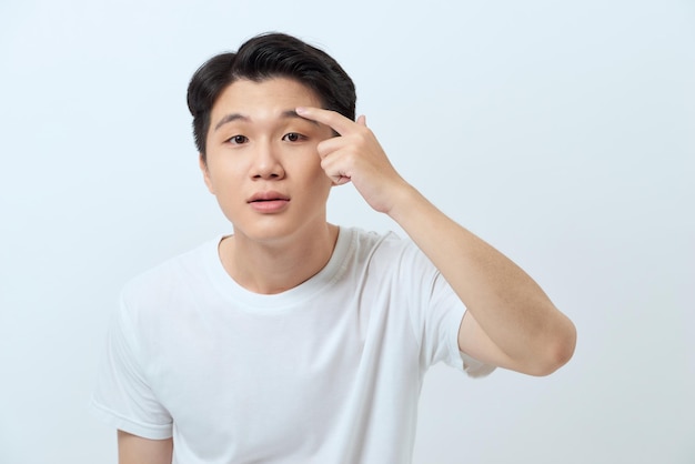 Young attractive man checking his skin and touching wrinkles on his face