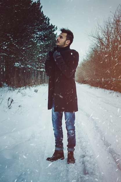 Young attractive man embracing the snow in winter. Closeup Portrait