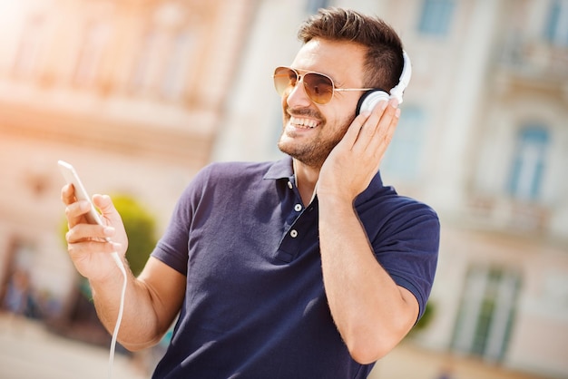 Photo young attractive man is smiling while wearing headphones