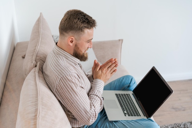 Young attractive man sitting on sofa at home working on laptop online using