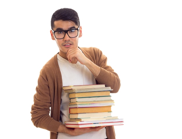 Young attractive man with black hair in white Tshirt brown cardigan holding a pile of books