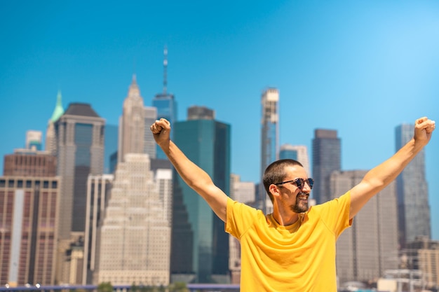 Young attractive man with raised arms happy smiling win celebration in the city skyline