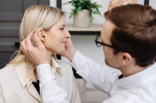 Photo a young attractive otolaryngologist doctor gives a consultation to a female patient a doctor explains how to wear a hearing aid to a woman