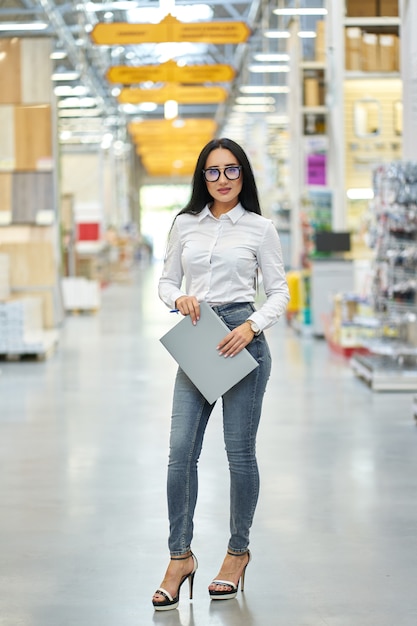 Young attractive positive girl seller on the background of the shopping center