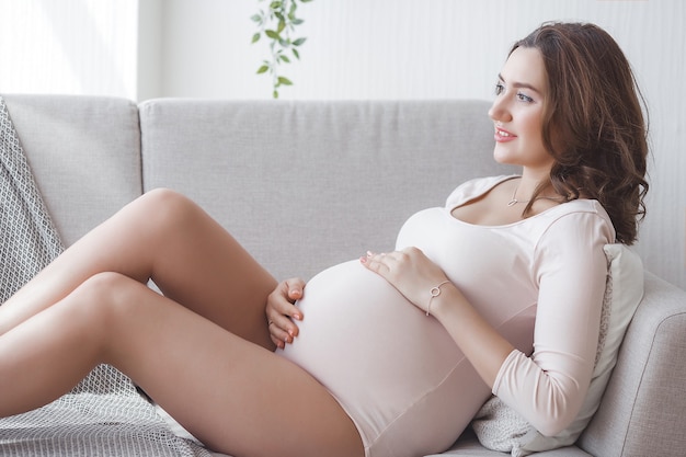 Young attractive pregnant woman at home. Close up portrait of expecting female.