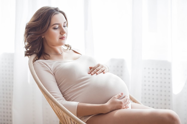 Young attractive pregnant woman at home. Close up portrait of expecting female.