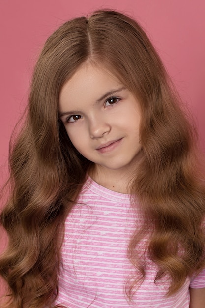 Young attractive redhead girl Caucasian smiling looking at camera. Shooting in studio on a pink background