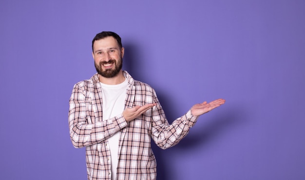 Young attractive smiling bearded man in casual clothes Pointing index finger aside