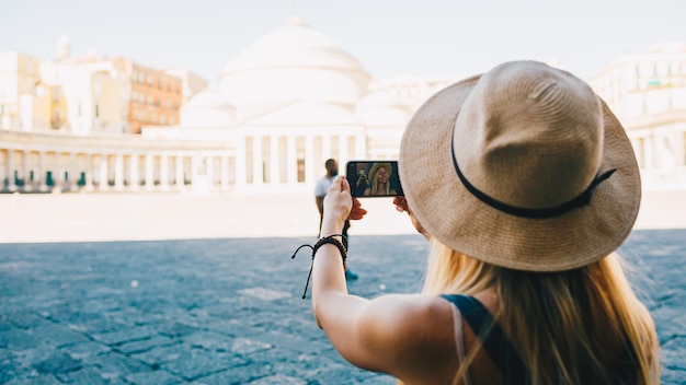 Young attractive smiling girl tourist exploring new city at summer