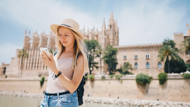 Young attractive smiling girl tourist exploring new city at summer