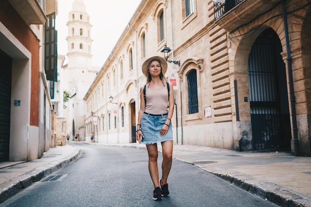 Young attractive smiling girl tourist exploring new city at summer