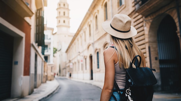 Young attractive smiling girl tourist exploring new city at summer