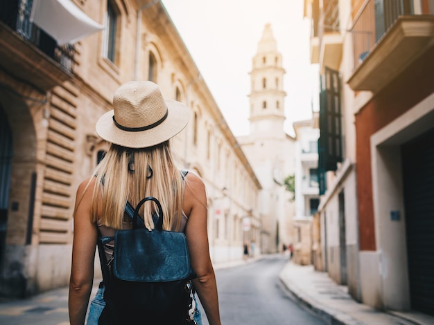 Young attractive smiling girl tourist exploring new city at summer