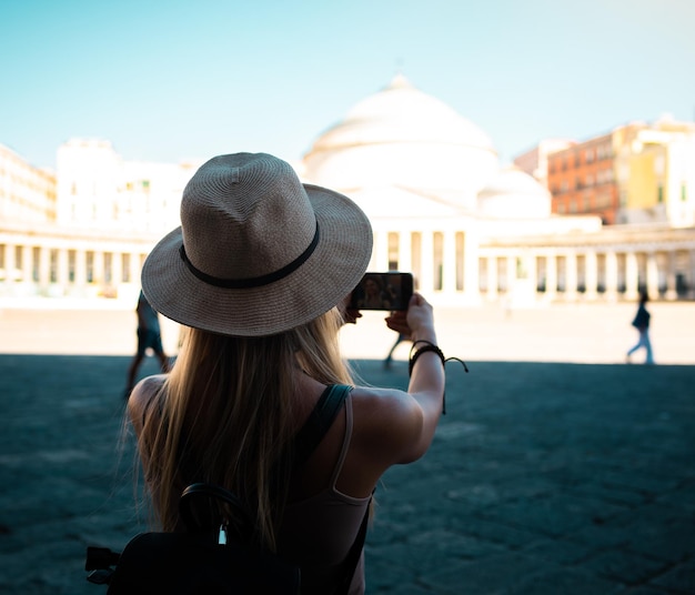 Young attractive smiling girl tourist in hat exploring new Europe city at summer holiday