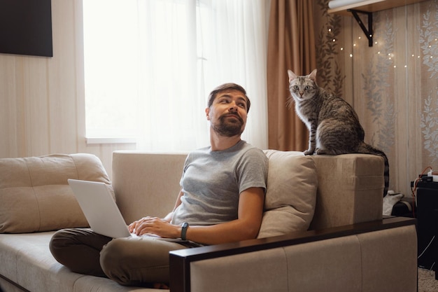 Young attractive smiling guy is browsing at his laptop