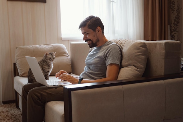 Young attractive smiling guy is browsing at his laptop