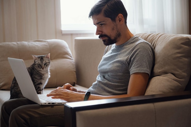 Young attractive smiling guy is browsing at his laptop