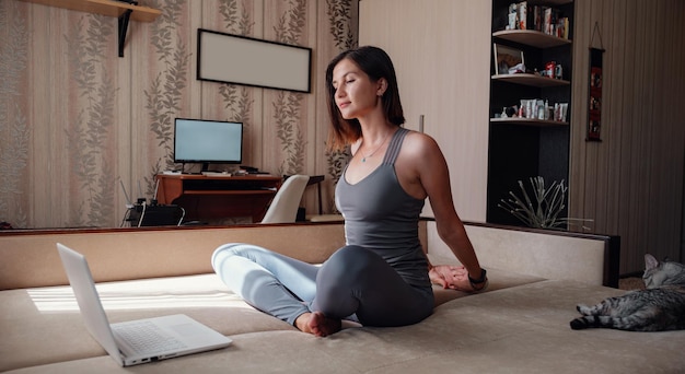 Young attractive smiling woman practicing yoga sitting in Half Lotus exercise