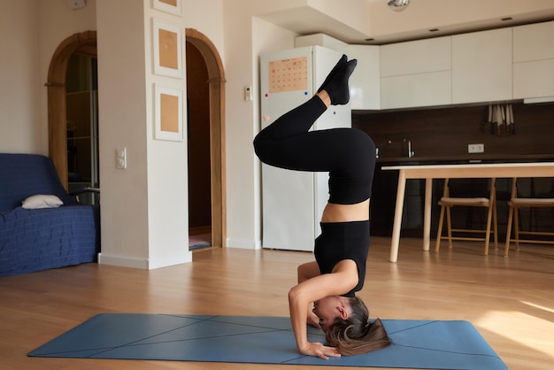 Young attractive smiling woman practicing yoga wearing sportswear pants and top indoor full length a