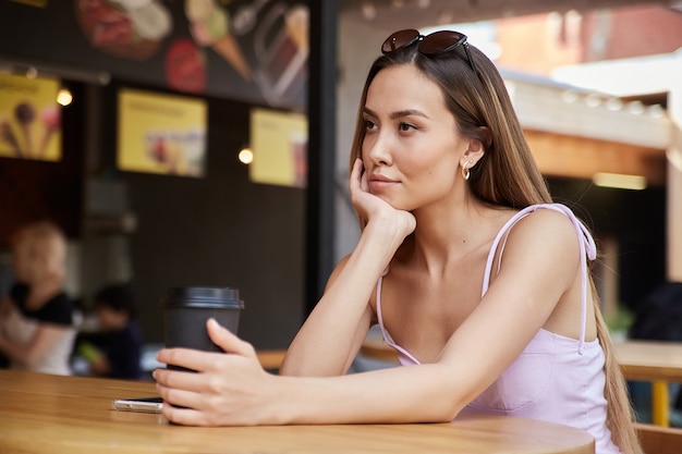 Young attractive stylish asian pretty girl sitting at dinery with cup of coffee