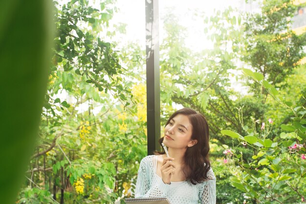 Young attractive sweet girl with notepad on a veranda. Spring mood.