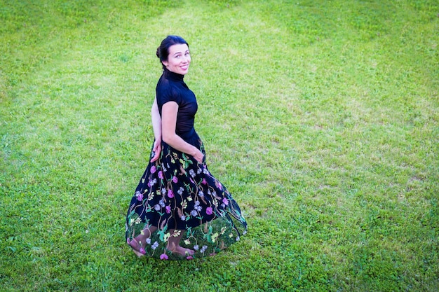 A young attractive woman in black clothes dansing in a backyard