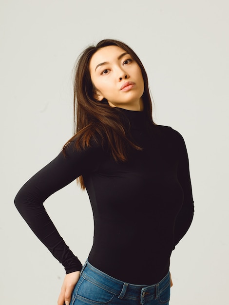 Young attractive woman in black turtleneck and jeans isolated on studio background