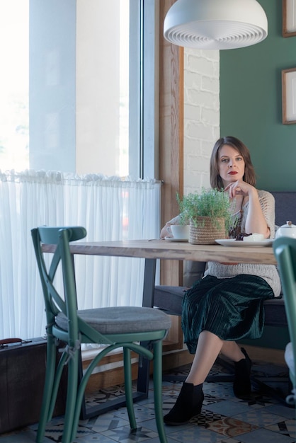 Young attractive woman in cafe looking at camera Business meeting Lonely woman sits in cafe with cup of coffee or tea