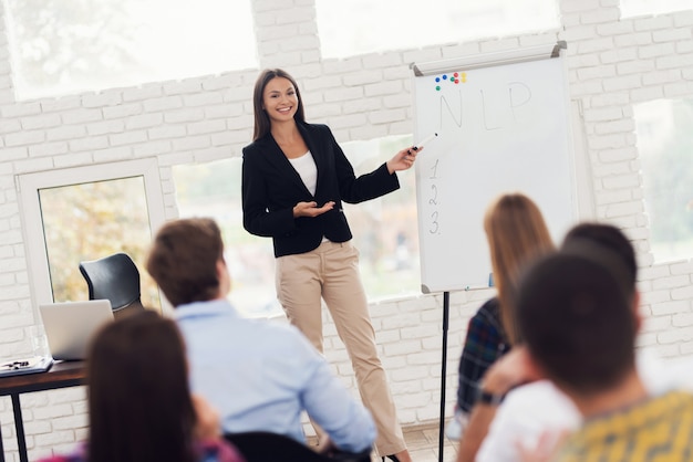 Young attractive woman coacher is conducting seminar.