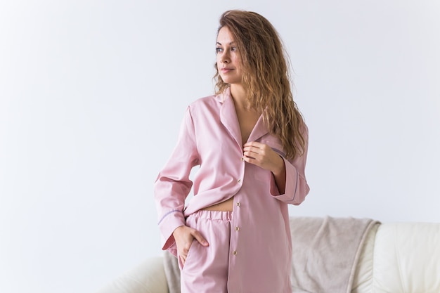 Young attractive woman dressed in beautiful colorful pajama posing as a model in her living room. Comfortable sleepwear, home relaxation and female fashion concept.