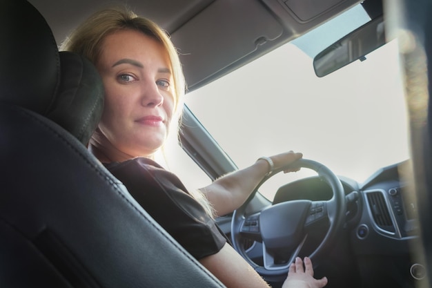 Young attractive woman drives a car Beautiful blonde woman with long hair in a car while driving