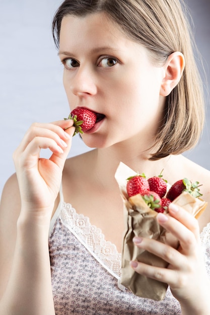 Young attractive woman eating fresh ripe strawberry